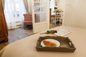 A room with a bed, a wooden door, a chair, and a tray with croissants. - Le Merlot du Marais - Steps from Pompidou (Paris -  4th Arrondissement)