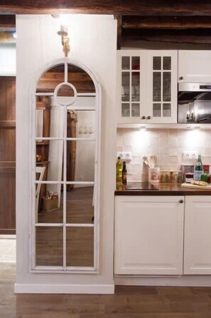 A kitchen with white cabinets, a wooden door, and a countertop with various items. - Le Merlot du Marais - Steps from Pompidou (Paris -  4th Arrondissement)