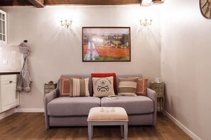 A cozy living room with a grey sofa, a matching ottoman, and a framed painting above. - Le Merlot du Marais - Steps from Pompidou (Paris -  4th Arrondissement)