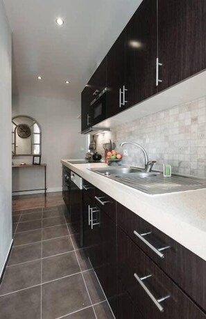 Una cocina moderna con armarios de madera oscura, una encimera blanca y un respuesto de azulejos.