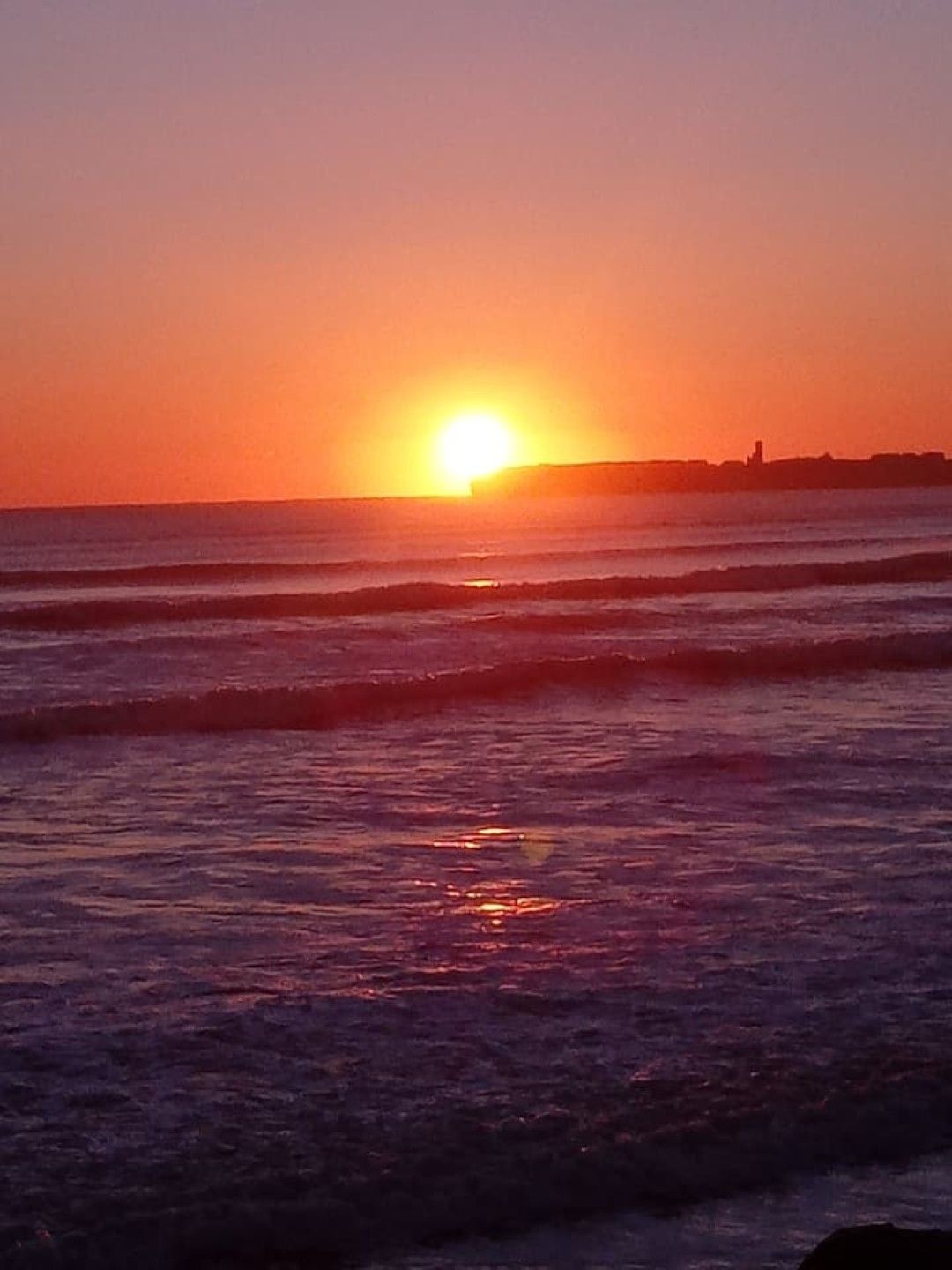 A sunset over the ocean with waves.