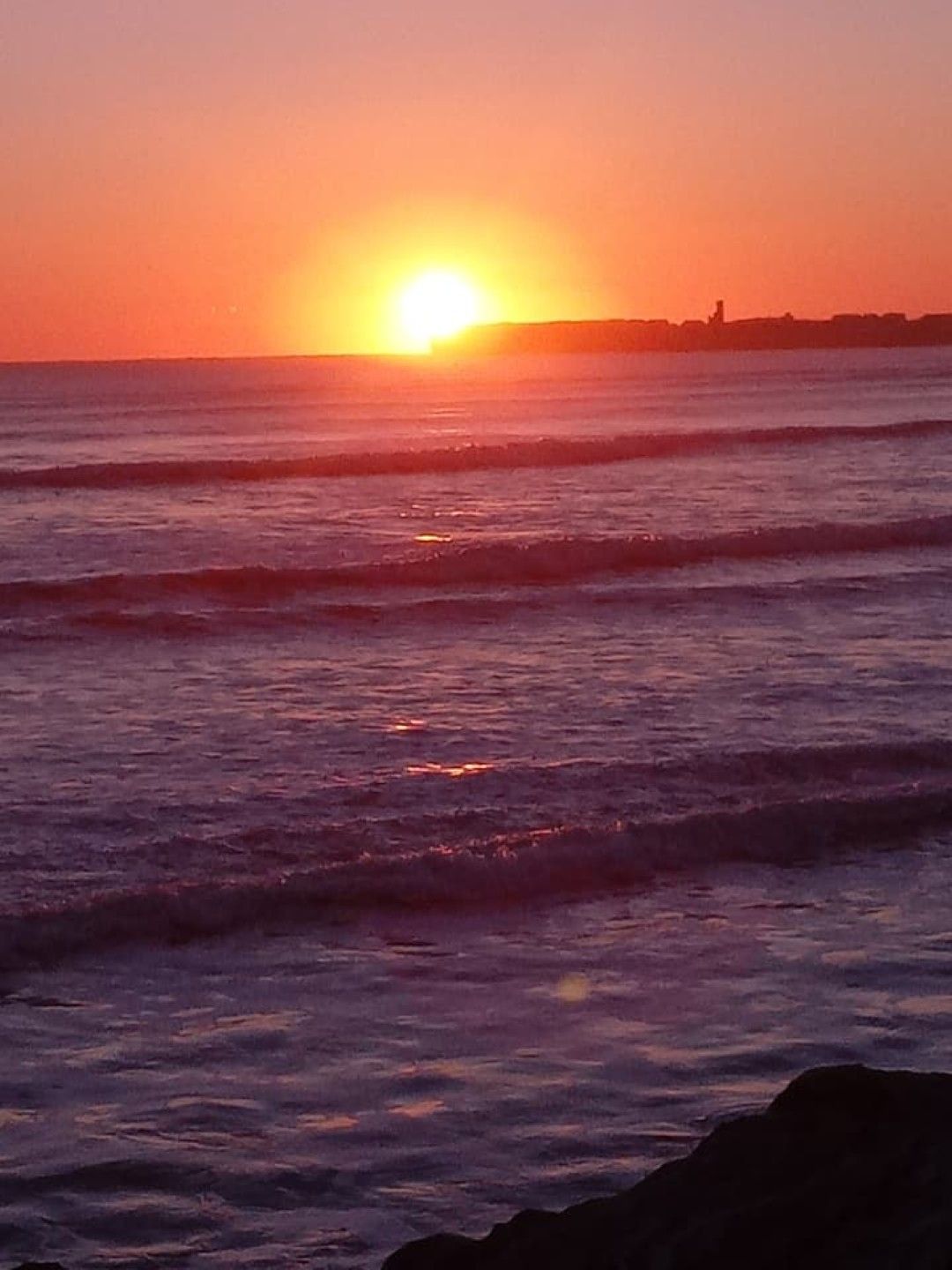 Un atardecer sobre el océano con olas.