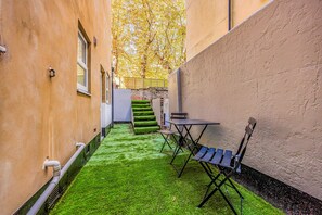 A narrow outdoor space with artificial grass, a table with chairs, and a staircase leading to an upper level. - Basement Flat Minutes From Pier And Beach - Pass the Keys (Portsmouth)