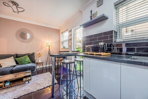 A modern kitchen with a bar area, a dining table, and a sofa in a living area. - Basement Flat Minutes From Pier And Beach - Pass the Keys (Portsmouth)