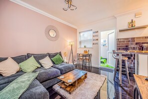 Un salon moderne avec un canapé gris, une table basse et une petite table d’appoint sur laquelle se trouve une lampe.