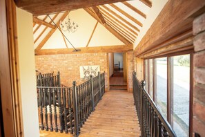 A wooden staircase with a brick wall and a chandelier. - The Threshing Barn - Pass the Keys (Blankney Fen)