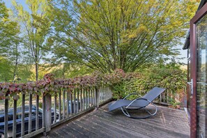 A wooden deck with a metal chair, surrounded by trees and a fence. - Chilterns Leafy Hillside Hideaway - Pass the Keys (High Wycombe)