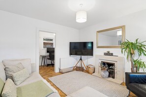 Ein Wohnzimmer mit einer Couch, einem Fernseher, einem Kamin und einem Spiegel.