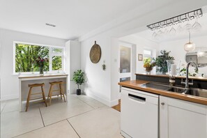 A modern kitchen with a window, bar stools, a dishwasher, and a wine rack. - Chilterns Leafy Hillside Hideaway - Pass the Keys (High Wycombe)