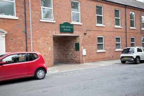Ein rotes Auto parkt vor einem Backsteinhaus mit einem Schild, auf dem 'Larchfield House' steht.
