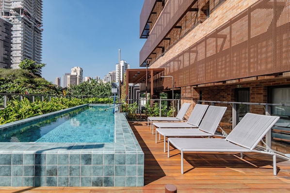 A rooftop pool with lounge chairs and a view of the city skyline. - Vom by Bhomy (São Paulo)