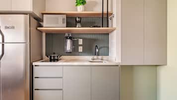 Een moderne keuken met een inbouwkoelkast, magnetron en koffiezetapparaat op een plank.
