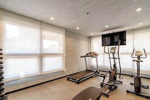 Een fitnessruimte met loopbanden, crosstrainers en een hometrainer.