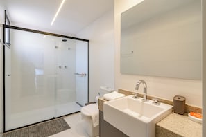 A modern bathroom with a glass-enclosed shower, a large sink, and a mirror above the sink. - Vom by Bhomy (São Paulo)