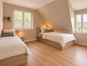 A bedroom with two beds, a nightstand, a lamp, and a window with blinds. - Schmiede II - Vacation Home for 8 People, 4 Bedrooms & Garden (Dagebüll)