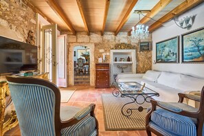 Ein gemütliches Wohnzimmer mit Sofa, Sesseln, einem Couchtisch und einem Fernseher.