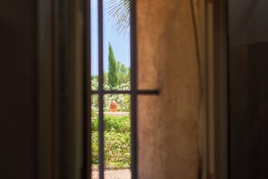 Ein Fenster mit Blick auf einen Garten und einen hohen Baum.