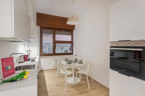 Une cuisine compacte comprenant une table à manger, des chaises, une fenêtre et un four encastré.