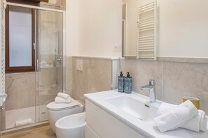 Et badeværelse med bruser, toilet, vask og et spejl.
