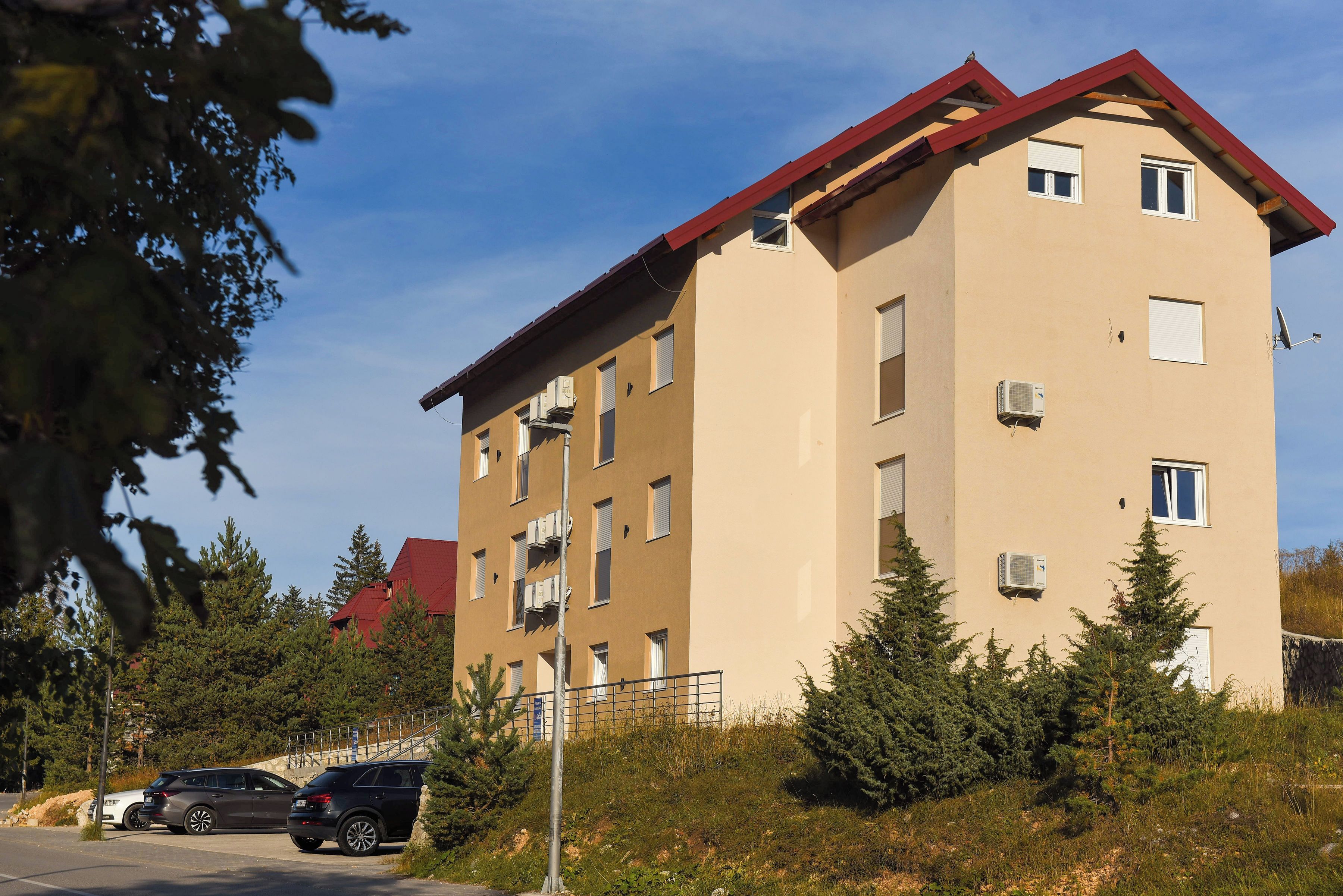 A multi-story residential building with balconies, air conditioning units, and a red roof.