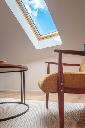 Ein Zimmer mit einem Oberlicht, einem runden Tisch, einem Holzstuhl und einem gemusterten Teppich.