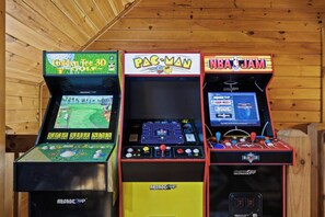 Drei Spielautomaten mit verschiedenen Spielen: Golf Tee 3D, Pac-Man und NBA Jam.