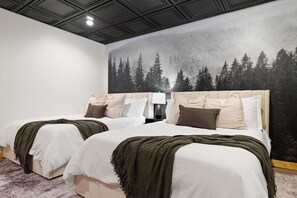Ein Hotelzimmer mit zwei Betten, einer Waldlandschaft an der Wand und einem modernen Deckenstil.