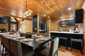 Ein modernes Interieur einer Blockhütte mit Essbereich, Küche und Kamin.
