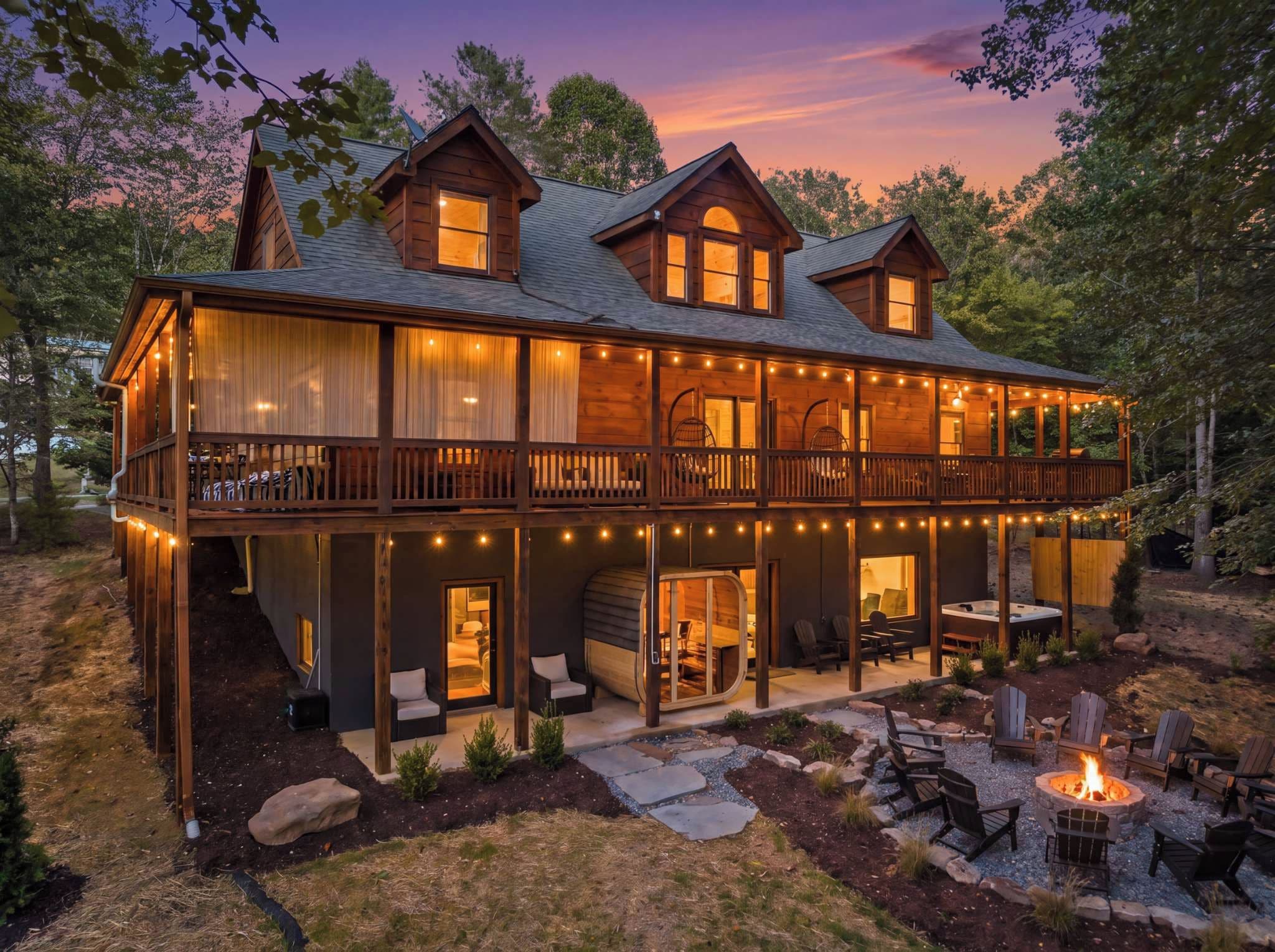 A two-story wooden cabin with a balcony, outdoor seating, and a fire pit.