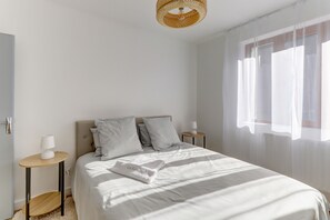 A minimalist bedroom with a bed, bedside tables, a hanging light fixture, and sheer curtains. - La Kaz - Proche de Montluçon (Néris-les-Bains)