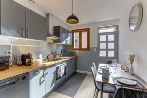 Eine moderne Küche mit Backofen, einer Kaffeemaschine und einem Essbereich mit Tisch für zwei Personen.