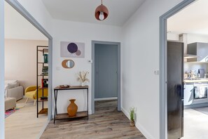A modern living room with a sofa, a coffee table, a bookshelf, and a door leading to another room. - La Kaz - Proche de Montluçon (Néris-les-Bains)