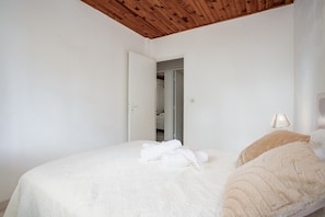 Une chambre à coucher avec un lit, une porte donnant sur une salle de bain et un plafond en bois.