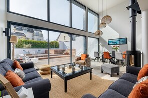A modern living room with a glass wall, a fireplace, and a dining area. - Ker Valy - Piscine privée et chauffée (La Trinite-sur-Mer)