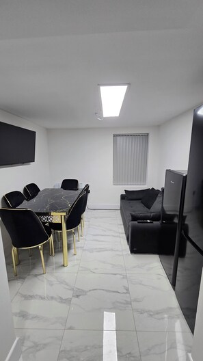 A modern living room with a dining area, a flat-screen TV, and a sofa. - Spacious 6-Bedrooms all En-suite House Stafford (Stafford)