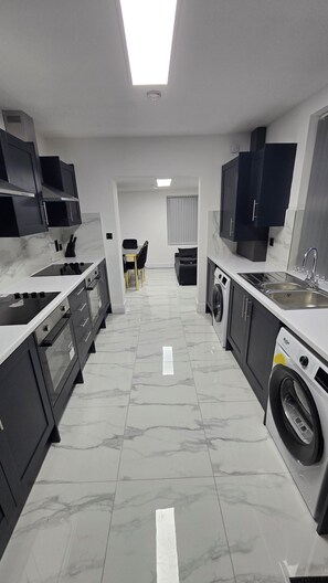 Une cuisine moderne dotée d’un îlot central, d’appareils électroménagers intégrés et d’un lave-linge.