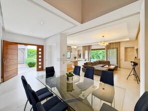 Ein modernes Wohnzimmer mit einem Glastisch, Sofas und Blick auf einen Pool.