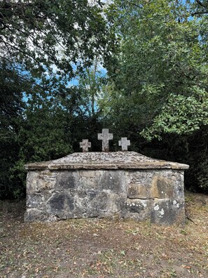 A stone structure with three crosses, surrounded by dense foliage. - Your Perfect Stay Near Pamplona (Ansoáin)