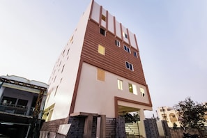 Ein mehrstöckiges Gebäude mit moderner Architektur, das Backstein und Putzfassaden, zahlreiche Fenster und einen ehrfurchtgebietenden Eingang kombiniert.
