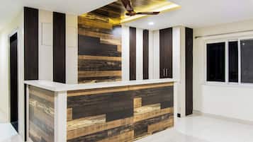 A modern reception desk with a wooden panel design, a ceiling fan, and a window with a view.
