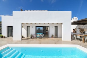 A modern white building with a pool, outdoor seating, and a clear sky. - Fantastic 3-bedroom house with heated pool in Tías perfect for your getaway (Tías)