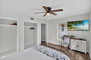 A bedroom with a bed, a ceiling fan, a wardrobe, a desk with a chair, and a TV mounted on the wall. - Vibrant 3BR Home, Blue Kitchen & Game Room (Abilene)