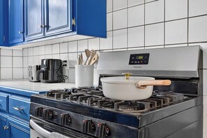 A kitchen with a stove, a pot on the burner, and a coffee maker on the counter. - Vibrant 3BR Home, Blue Kitchen & Game Room (Abilene)