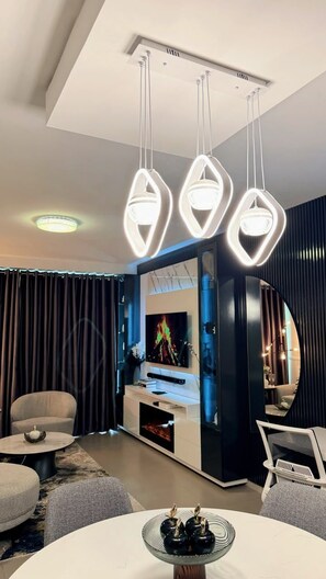 A modern living room with a central entertainment unit, a round coffee table, and a seating area with sofas. - Fantastic 2-bedroom apartment with AC in vibrant Sandton (Sandton)