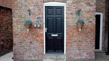 A black door with a white frame, flanked by two hanging flower baskets.