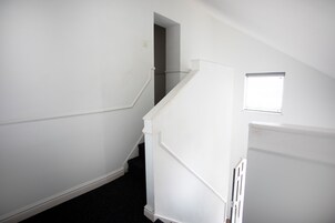 A staircase with white walls and a dark carpet leading to a landing.