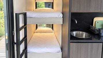 Une petite chambre avec des lits superposés et un coin cuisine.