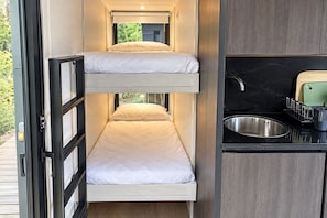 Una habitación pequeña con literas y un kitchenette.