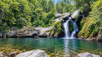 Un paysage naturel comprenant une cascade, de l’eau claire et une végétation luxuriante.