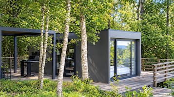 Una estructura moderna al aire libre con cerramiento de vidrio, una terraza y zona de barbacoa.
